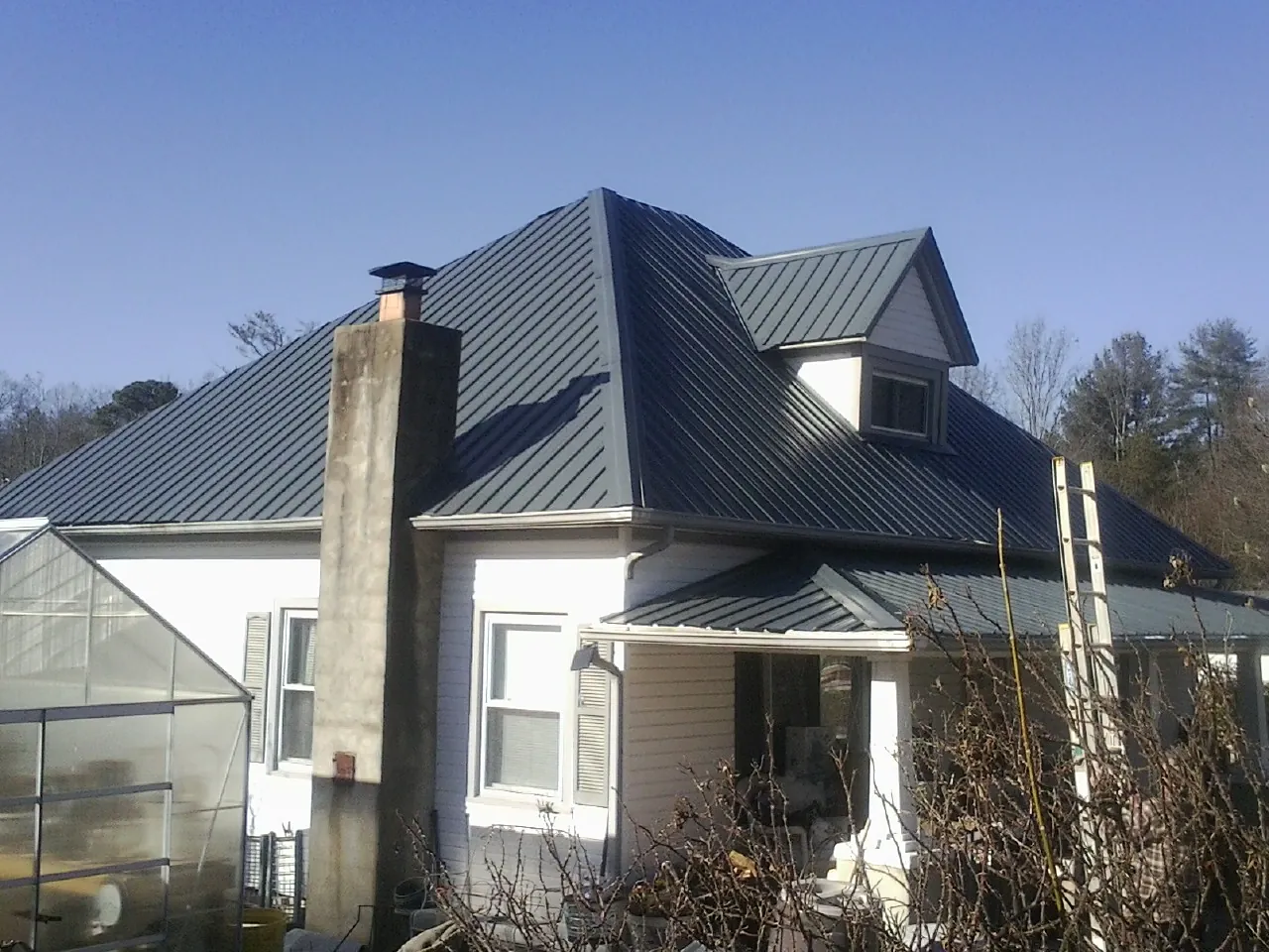 Dark blue standing seam metal roof on a white farmhouse with dormer — Slate & Tile Roof Repair by Roofing Brothers in Fort Belvoir