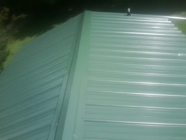 New green metal panels meeting at the ridge of a roof — Flat Roof Repair work by our crew in Fort Belvoir