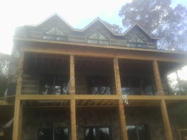 Dormers and porch framing on a large log home under construction — Roof Coating work by our crew in Fort Belvoir