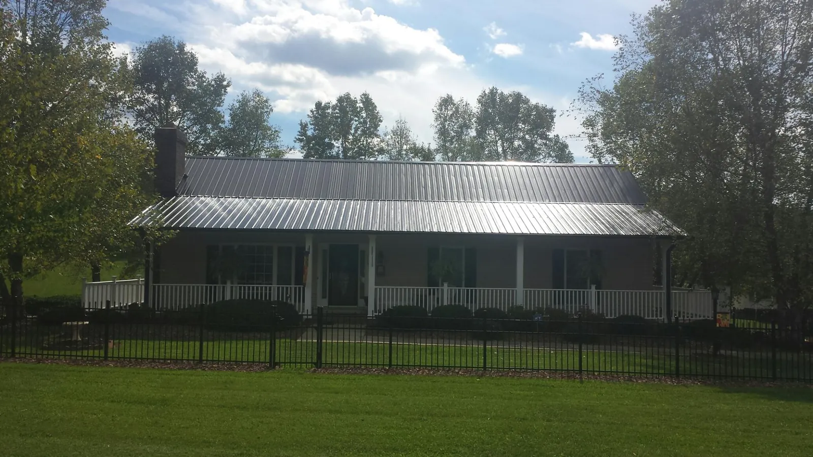 Gray metal roof on a brick ranch with a full width front porch — Gutter Guard Installation work by our crew in Fort Belvoir