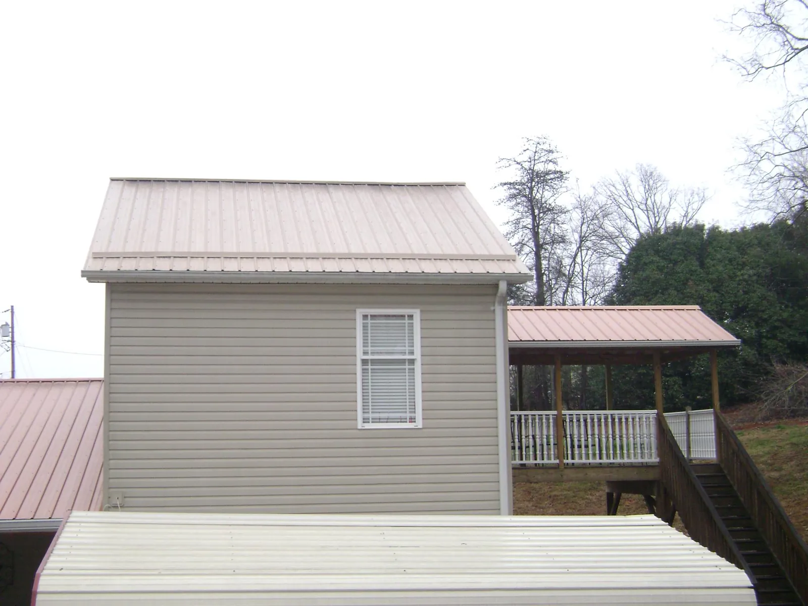 Tan metal roofs on a two story addition and attached porch, from a Roof Replacement job in Fort Belvoir