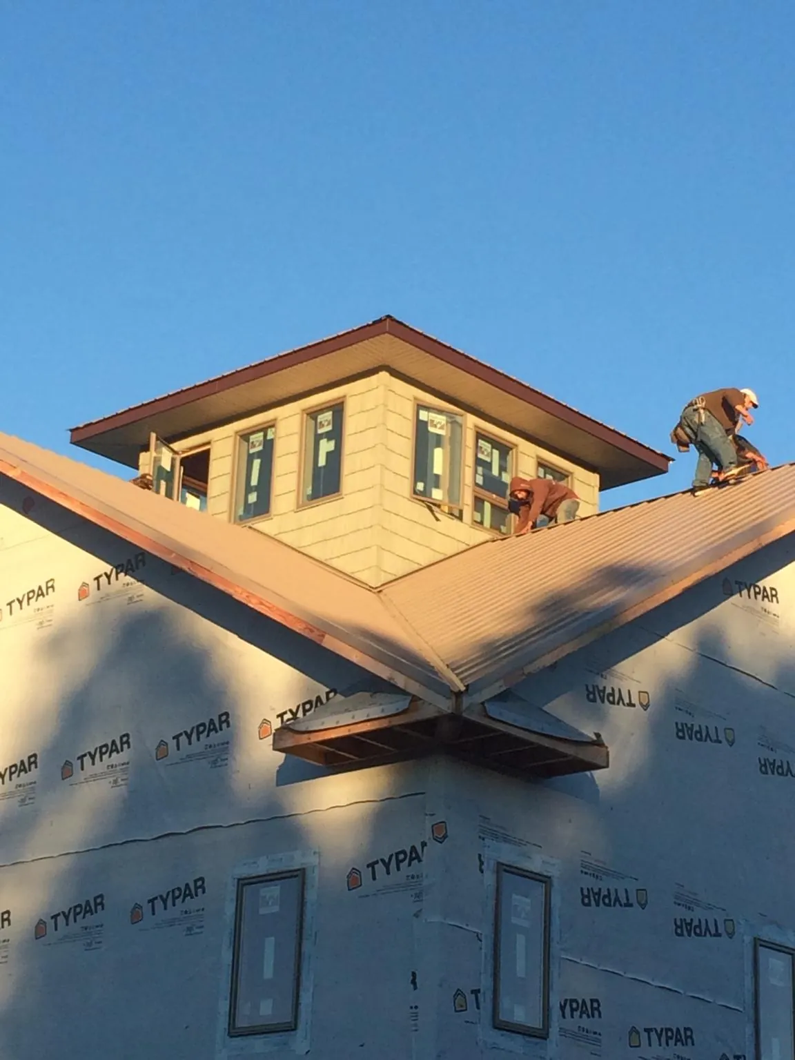 Roofers working around a rooftop cupola on a new metal roof at sunset — Roof Waterproofing in Fort Belvoir by Roofing Brothers